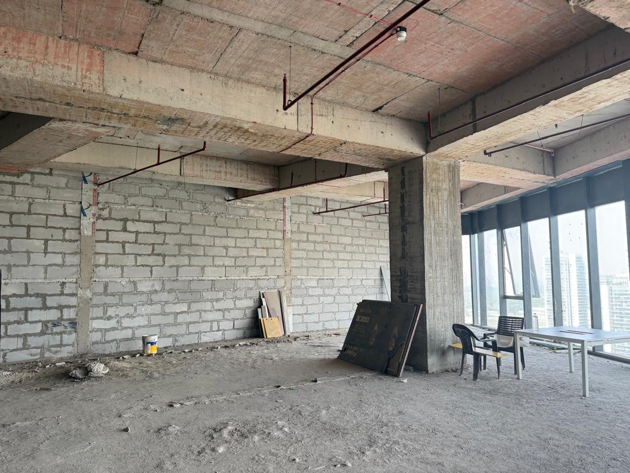 Raw site before fit-out: open floor and perimeter glazing · Saarthee Technology office, Magnum Global Park, Gurugram